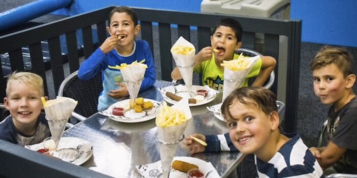 Kinderen eten lekkere patatjes na het spelen bij Jimmy's Speelparadijs.