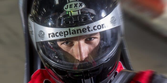 Close-up van een coureur met helm op in een kart op de kartbaan.