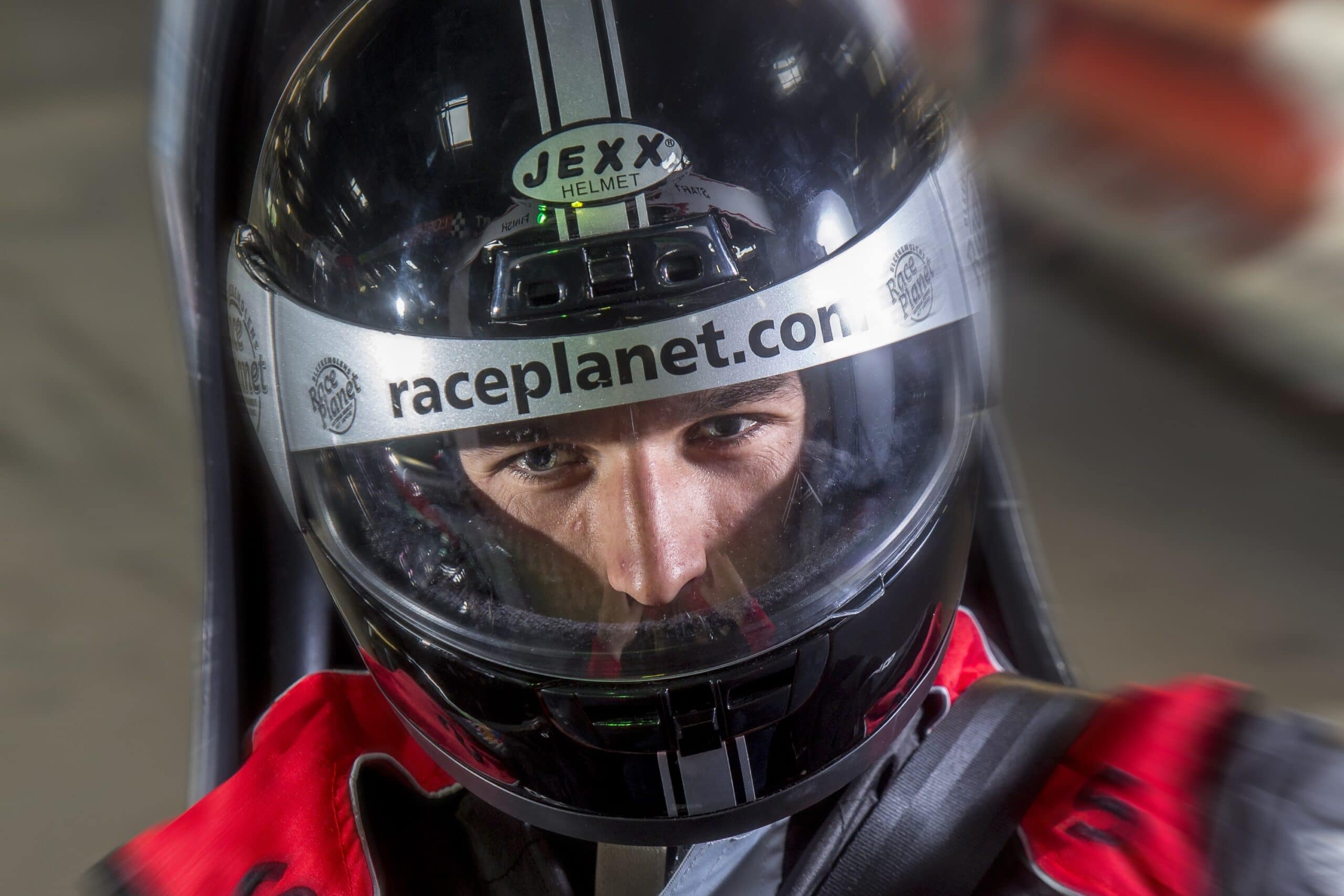 Close-up van een coureur met helm op in een kart op de kartbaan.