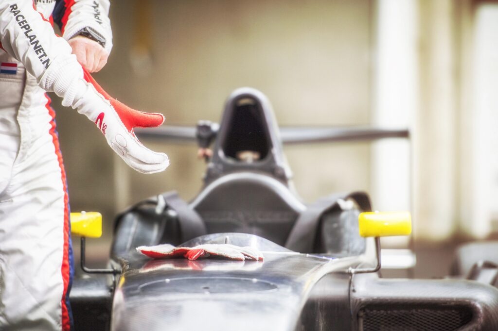 Coureur trekt handschoenen bij een Formule RP1 auto op het circuit voor de start van een race.