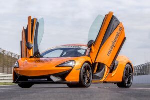 Oranje McLaren 540C met open vleugeldeuren op het rechte stuk van Circuit Zandvoort.