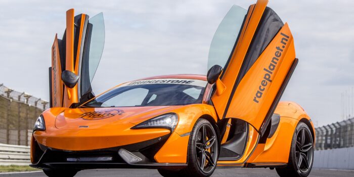 Oranje McLaren 540C met open vleugeldeuren op het rechte stuk van Circuit Zandvoort.