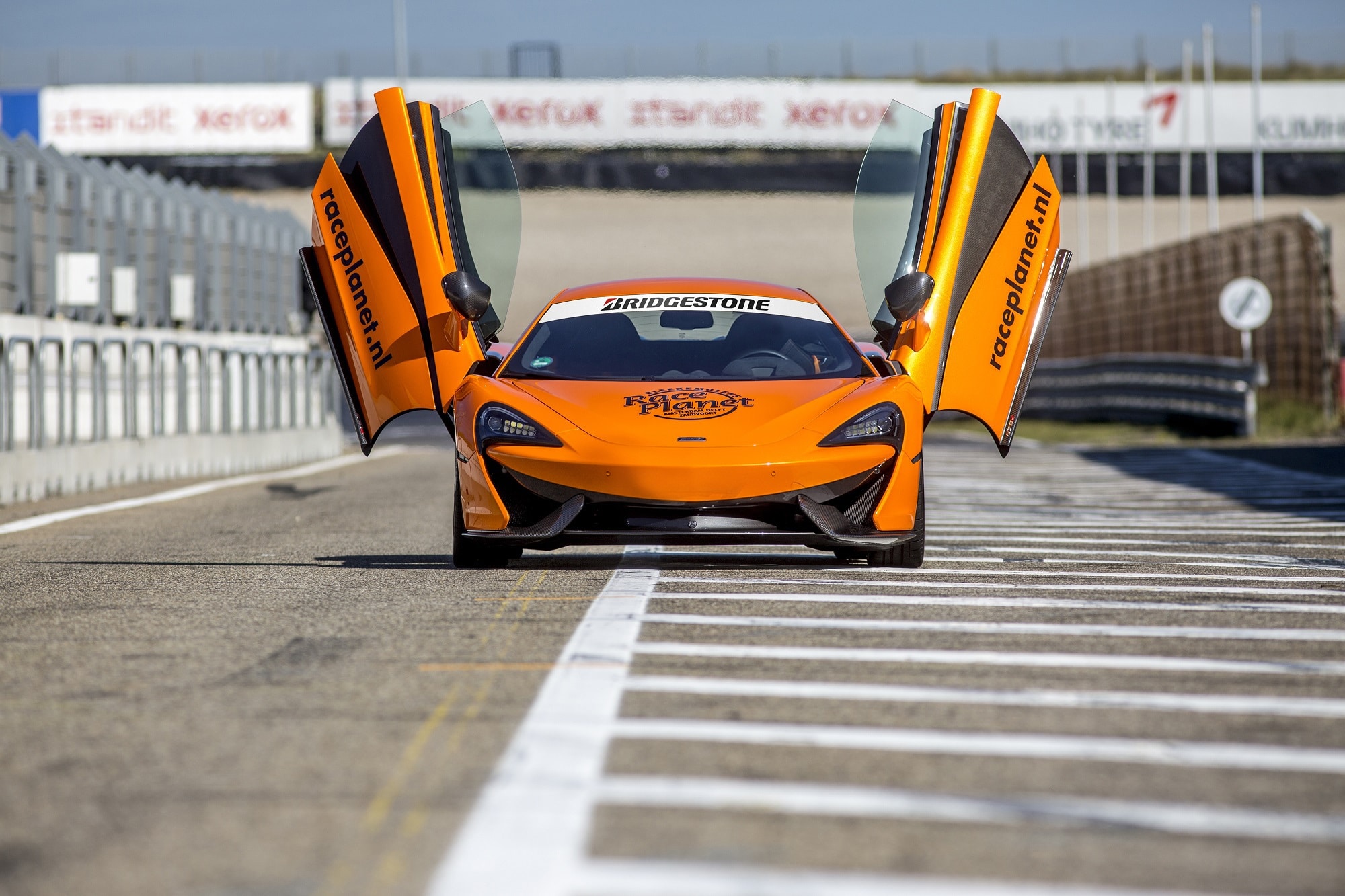 Oranje McLaren 540C in de pitstraat waarin een deelnemer zelf rijdt op Circuit Zandvoort tijdens de Race Experiences van Race Planet