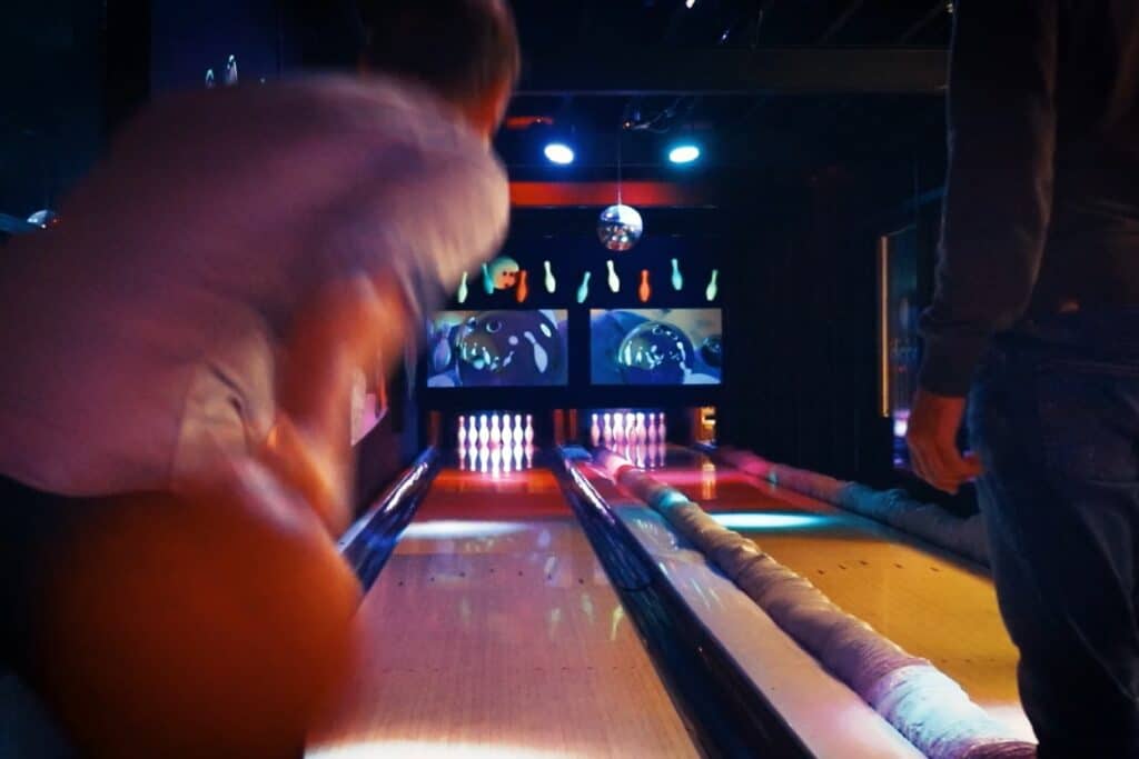 Bezoekers gooien een bowlingbal op de bowlingbaan voor een strike bij Race Planet Amsterdam en Delft.