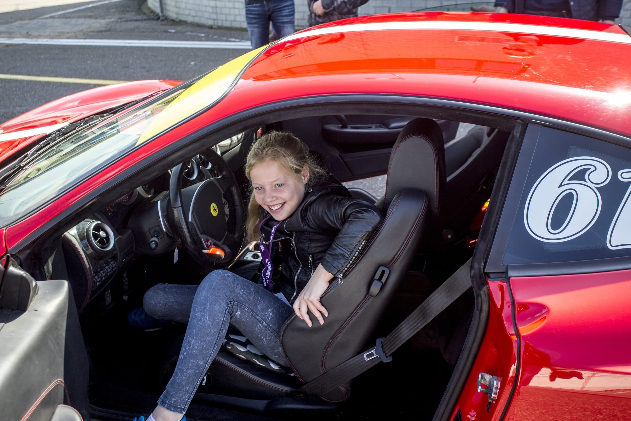 Meisje stapt uit een Ferrari van Race Planet op Circuit Zandvoort tijdens het Autorijden voor de Jeugd.